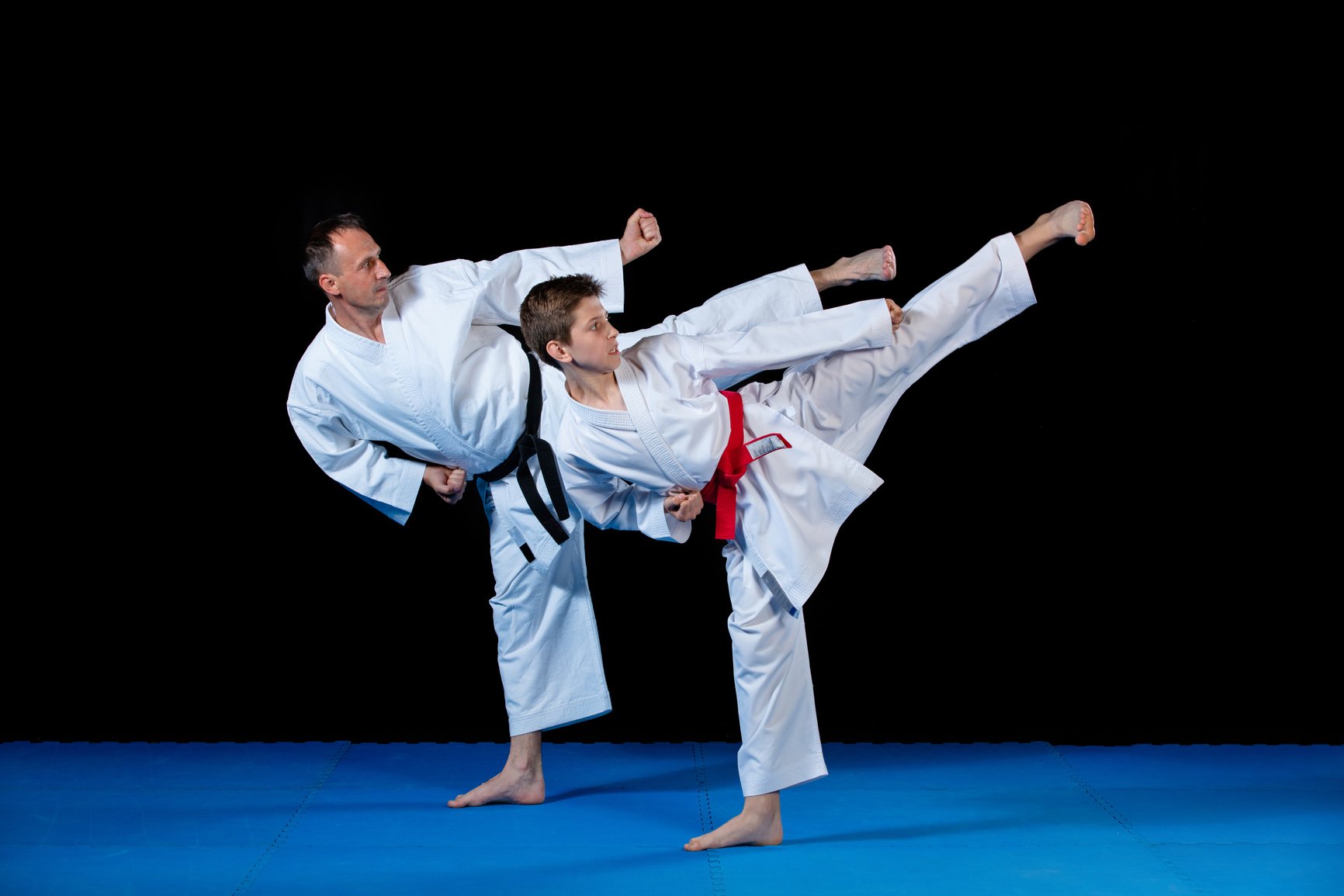 Male karate instructor training little children in dojo